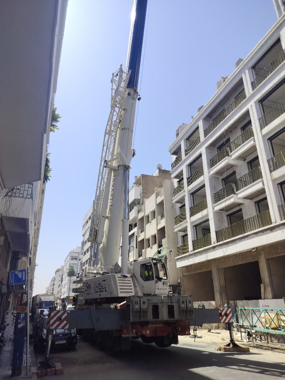 Une grue mobile tout-terrain devant un immeuble en construction, photo gratuite