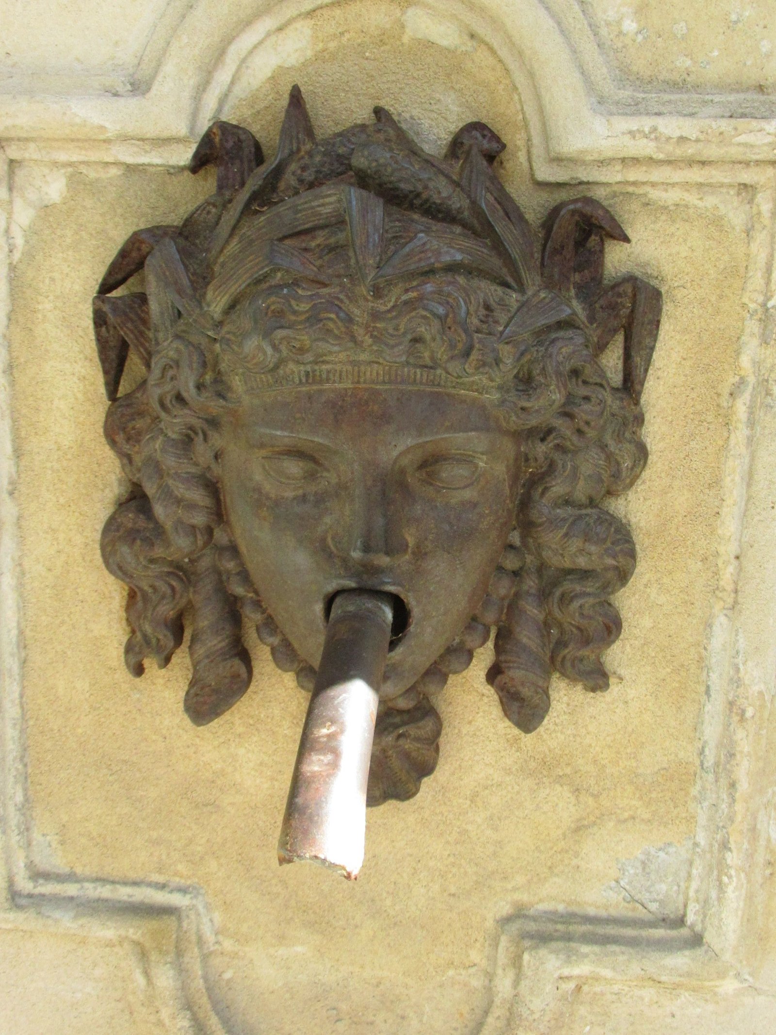 Sculpture d'une tête de femme sur une fontaine murale