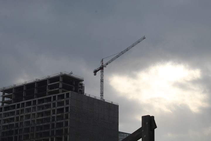 Un bâtiment en construction avec une grue sous un ciel nuageux et sombre photo gratuite