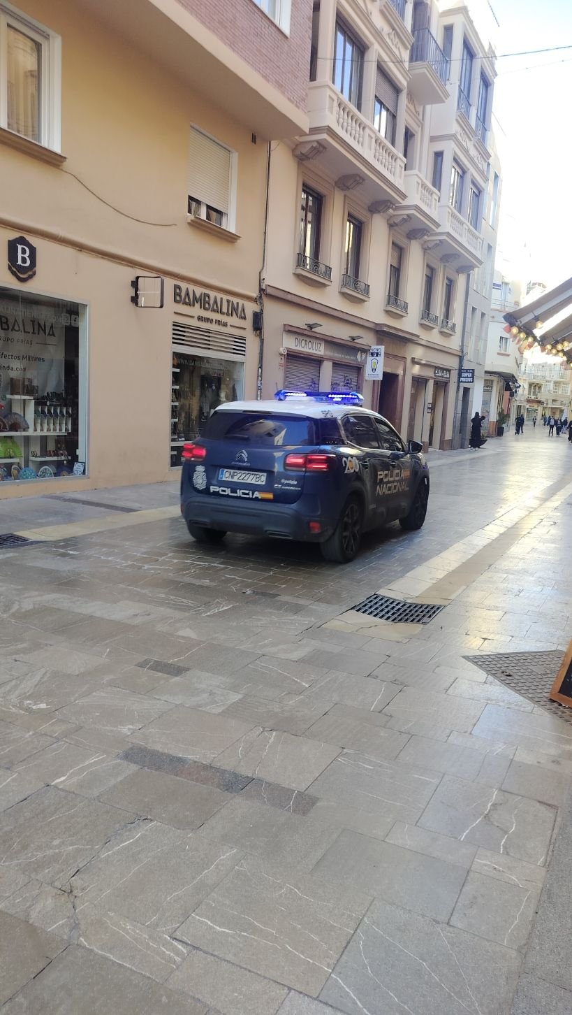 Une voiture de police garée dans une rue étroite devant un magasin, photo gratuite