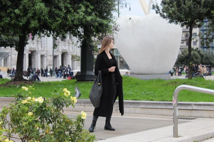 Femme habillée en noir, sac au bras, debout sur un espace public dans la ville de Milan Lombardie en Italie photo gratuite