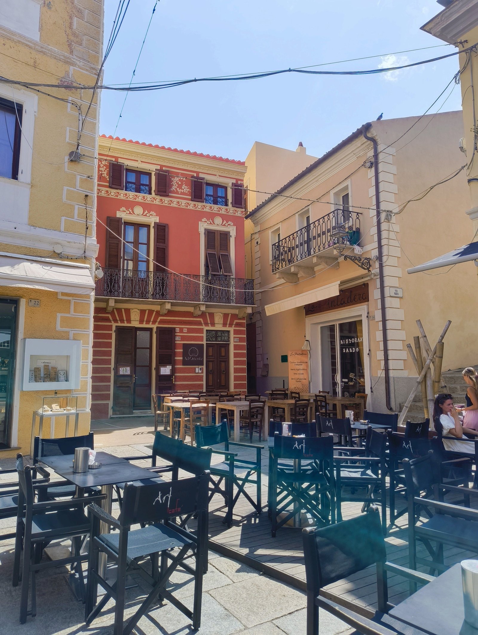 Des bâtiments qui environnent une terrasse avec des tables et des chaises, photo gratuite