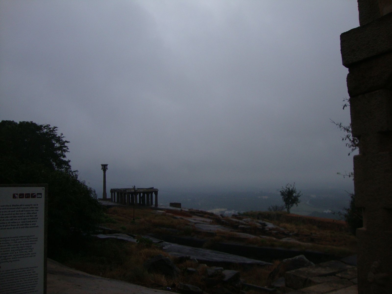 Une vue sur le paysage environnant, le temple de Chandragiri à Shravanabelagola, avec des structures architecturales et une végétation clairsemée sous un ciel nuageux, photo gratuite