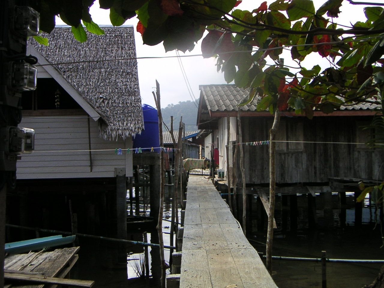 Un village de maisons sur pilotis, construit au-dessus de l'eau, avec une passerelle en bois reliant les habitations, photo gratuite