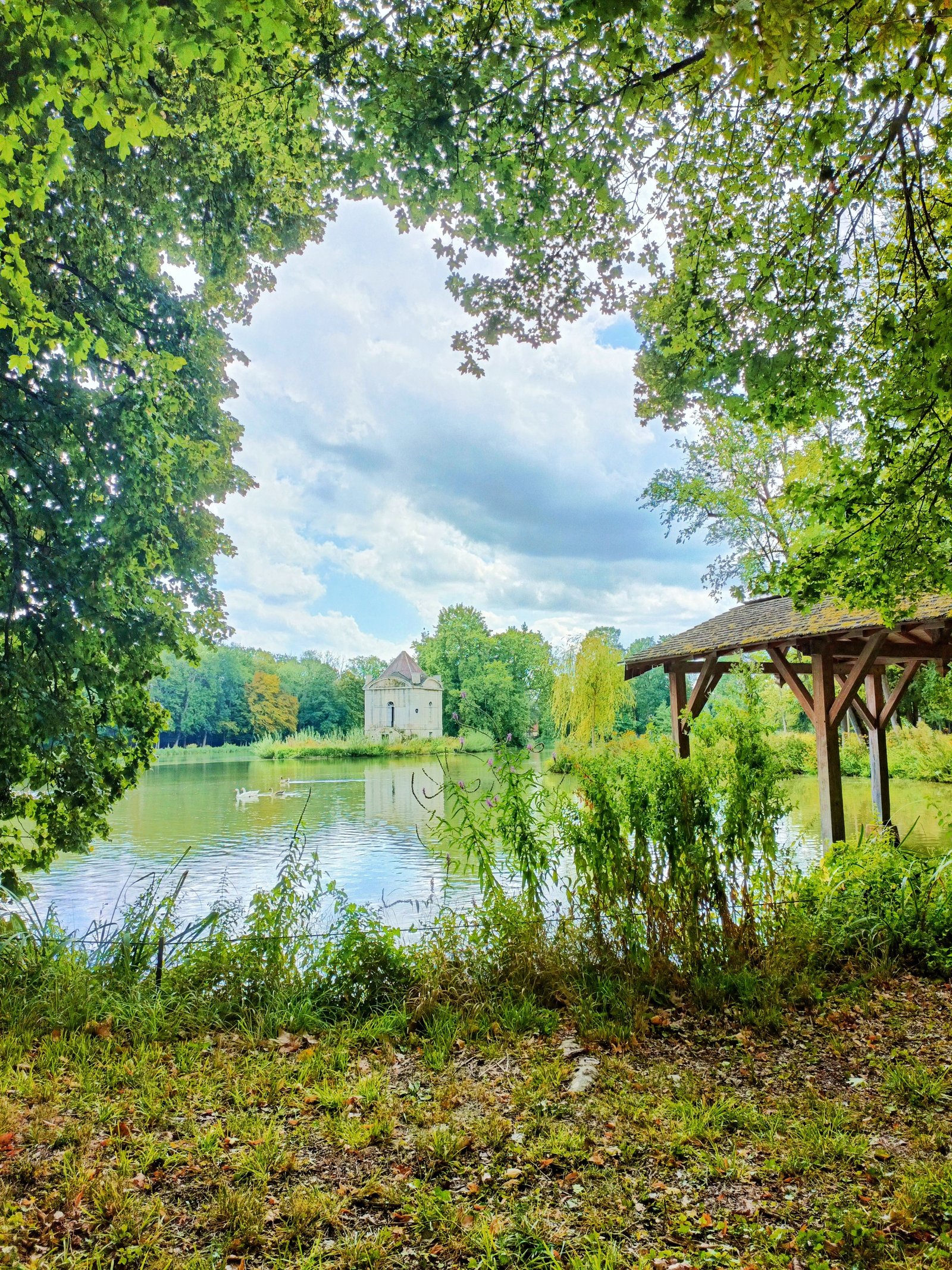 Un lieu avec un lac, un petit bâtiment en pierre au milieu de l'eau et une structure en bois, photo gratuite