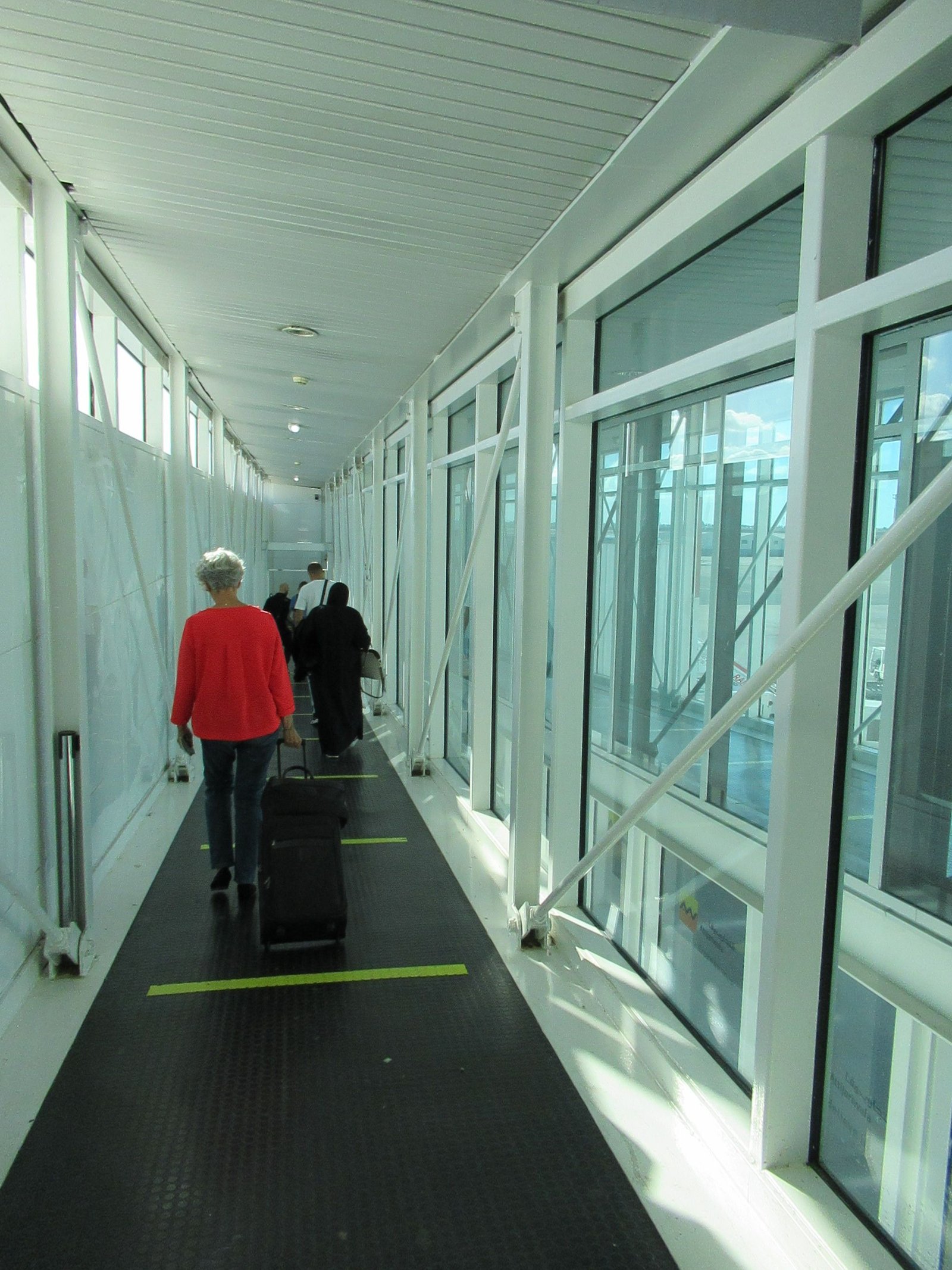 Personnes traversant une passerelle d'embarquement de passagers d'un avion