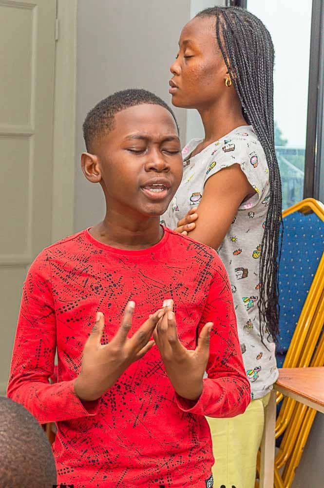 Un garçon en rouge, les yeux fermés et les mains levées photo gratuite