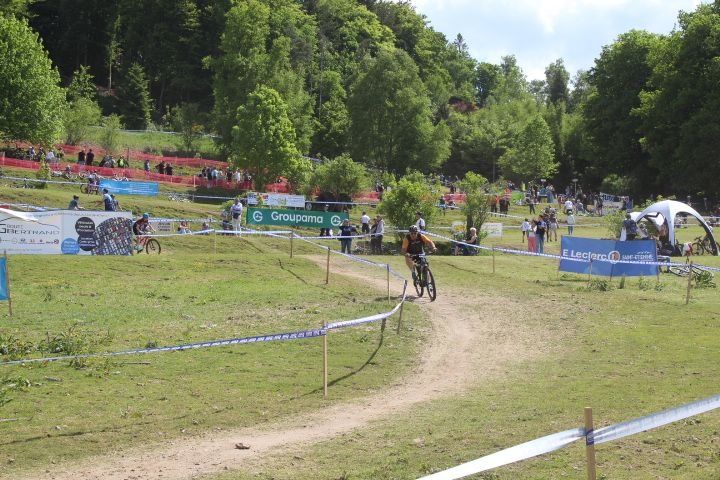 Course de VTT, le cycliste suit un parcours balisé par des rubans, avec des spectateurs observant depuis les collines environnantes photo gratuite