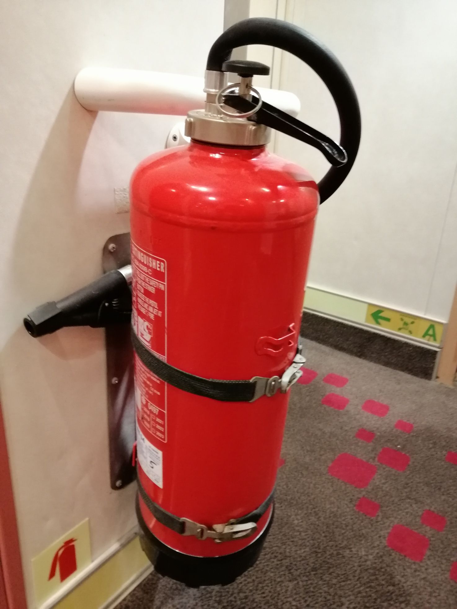 Extincteur accroché au mur dans un couloir