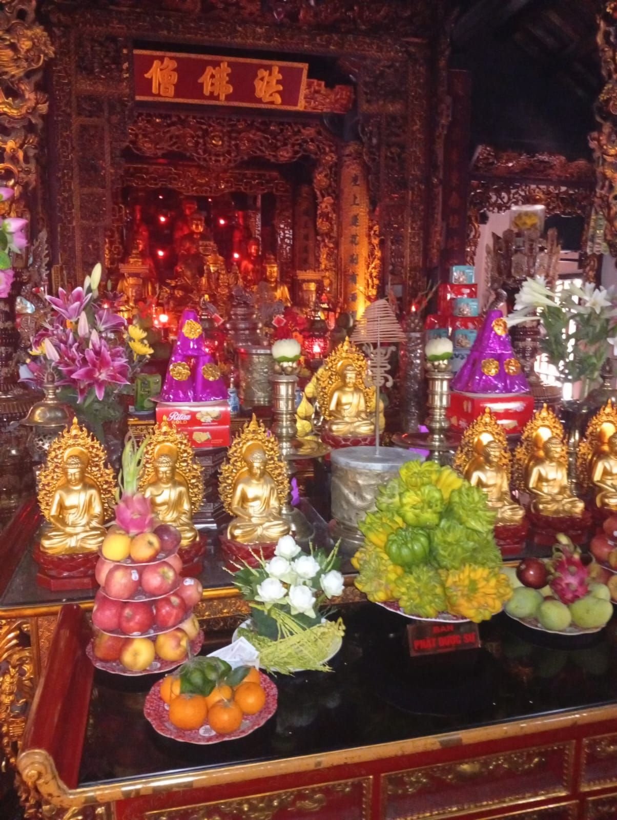 Autel décoré avec des statues de Bouddha dorées et des offrandes traditionnelles, Vietnam, photo gratuite