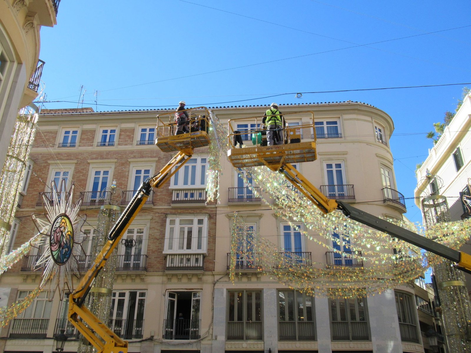 Des ouvriers installant des décorations de Noël dans une rue commerçante, photo gratuite