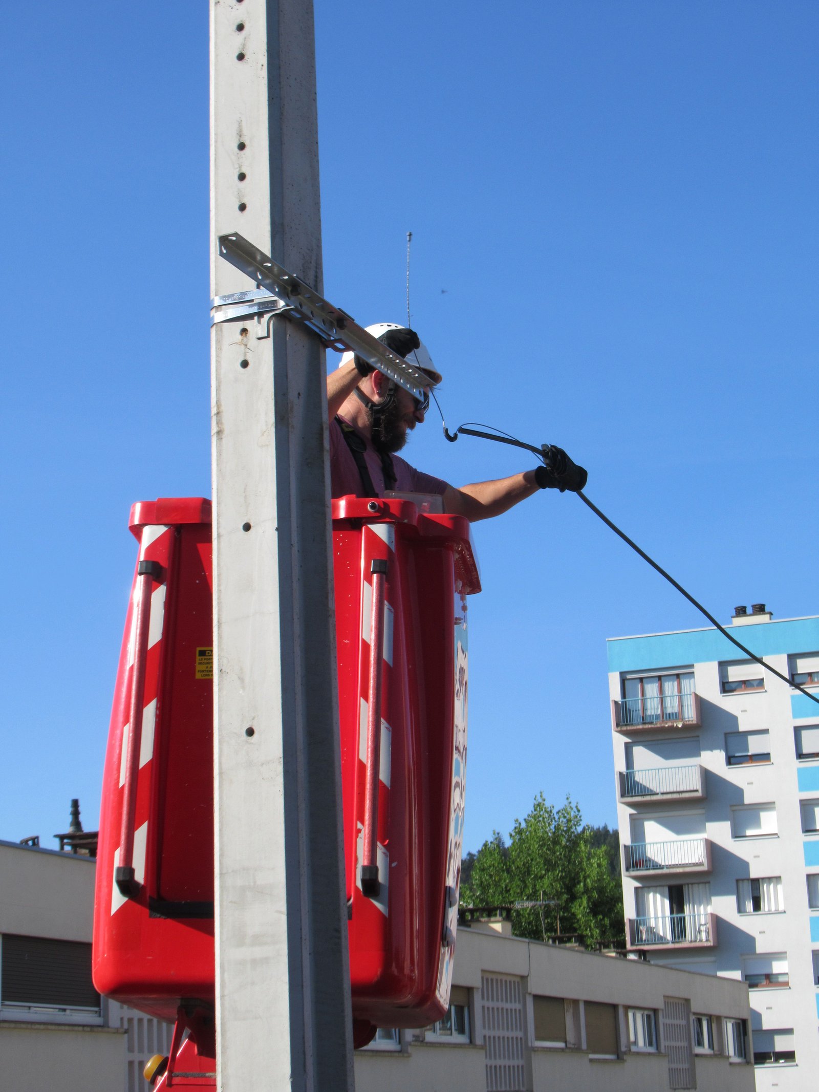 Electricien raccordant des câbles électriques sur une grue rouge