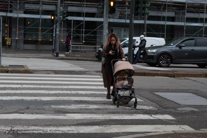 Une jeune maman qui traverse le goudron, passage piétons, avec un bébé sur une poussette dans la ville de Milan Lombardie en Italie photo gratuite