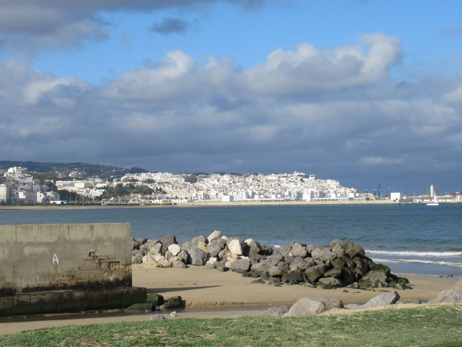 Vue de la ville de Tanger depuis la plage, morceaux de pierres à la plage photo gratuite