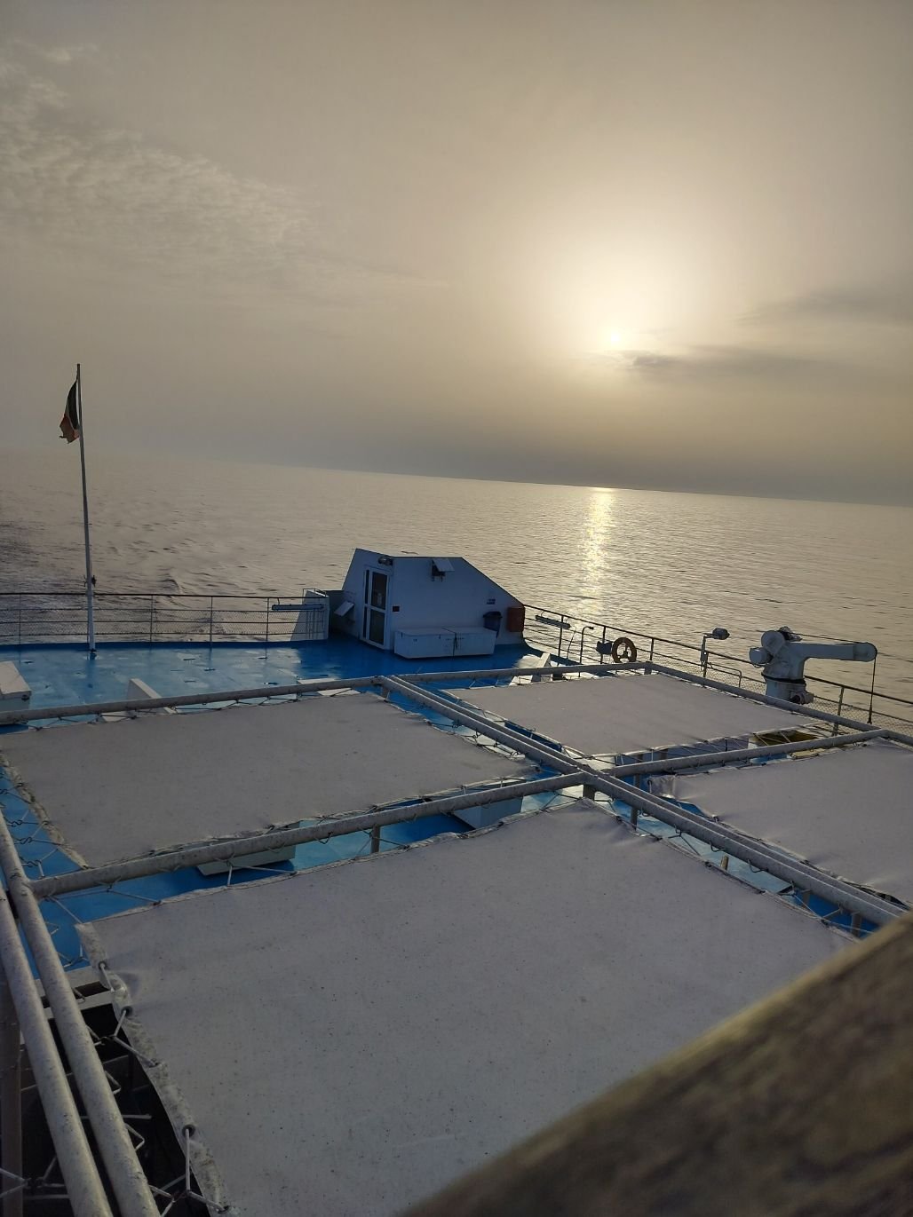 Le pont d'un bateau en pleine mer, au coucher du soleil, avec des zones couvertes des bâches, photo gratuite