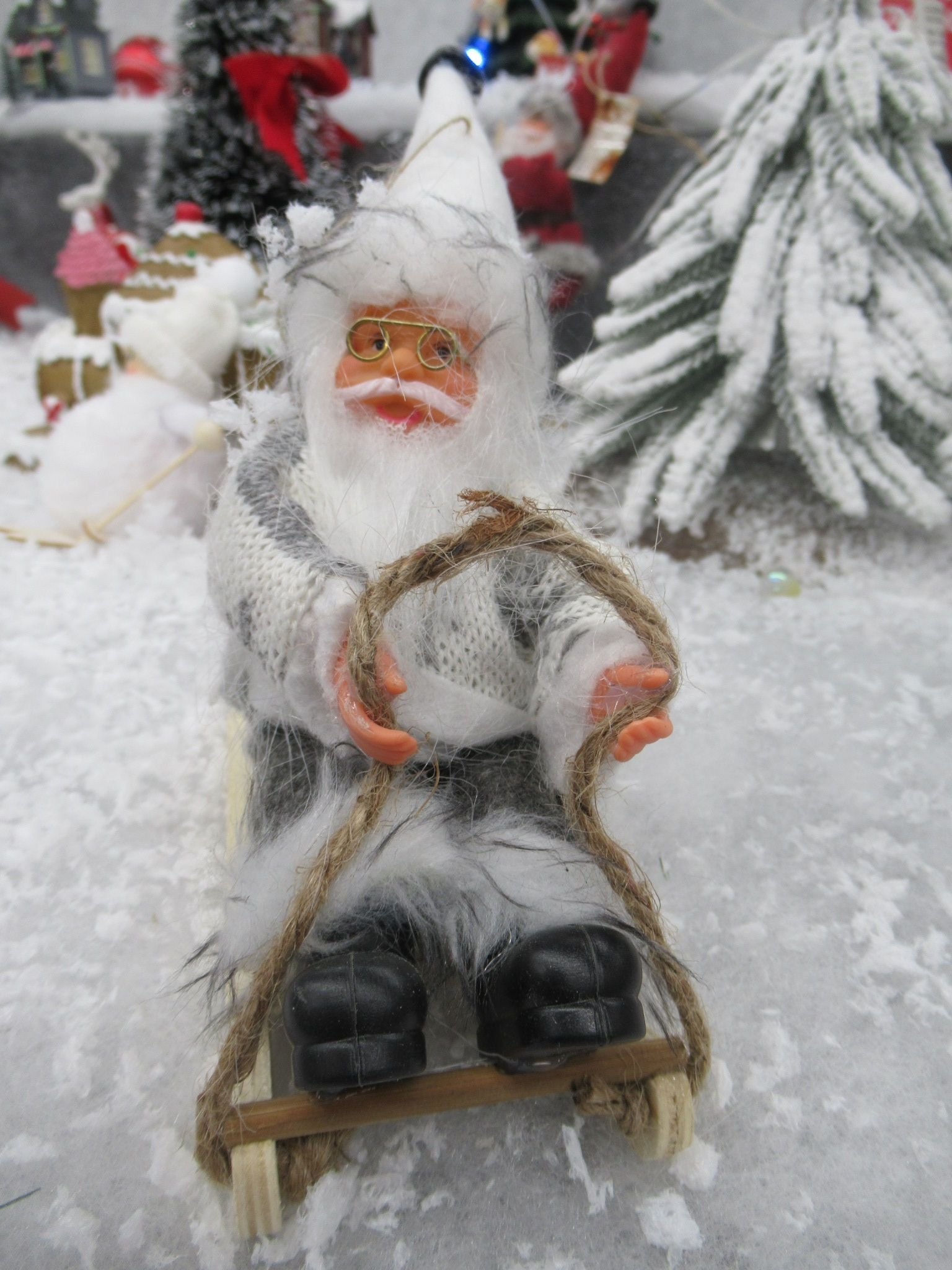 Une figurine décorative de Père Noël assise sur une petite luge en bois, photo gratuite