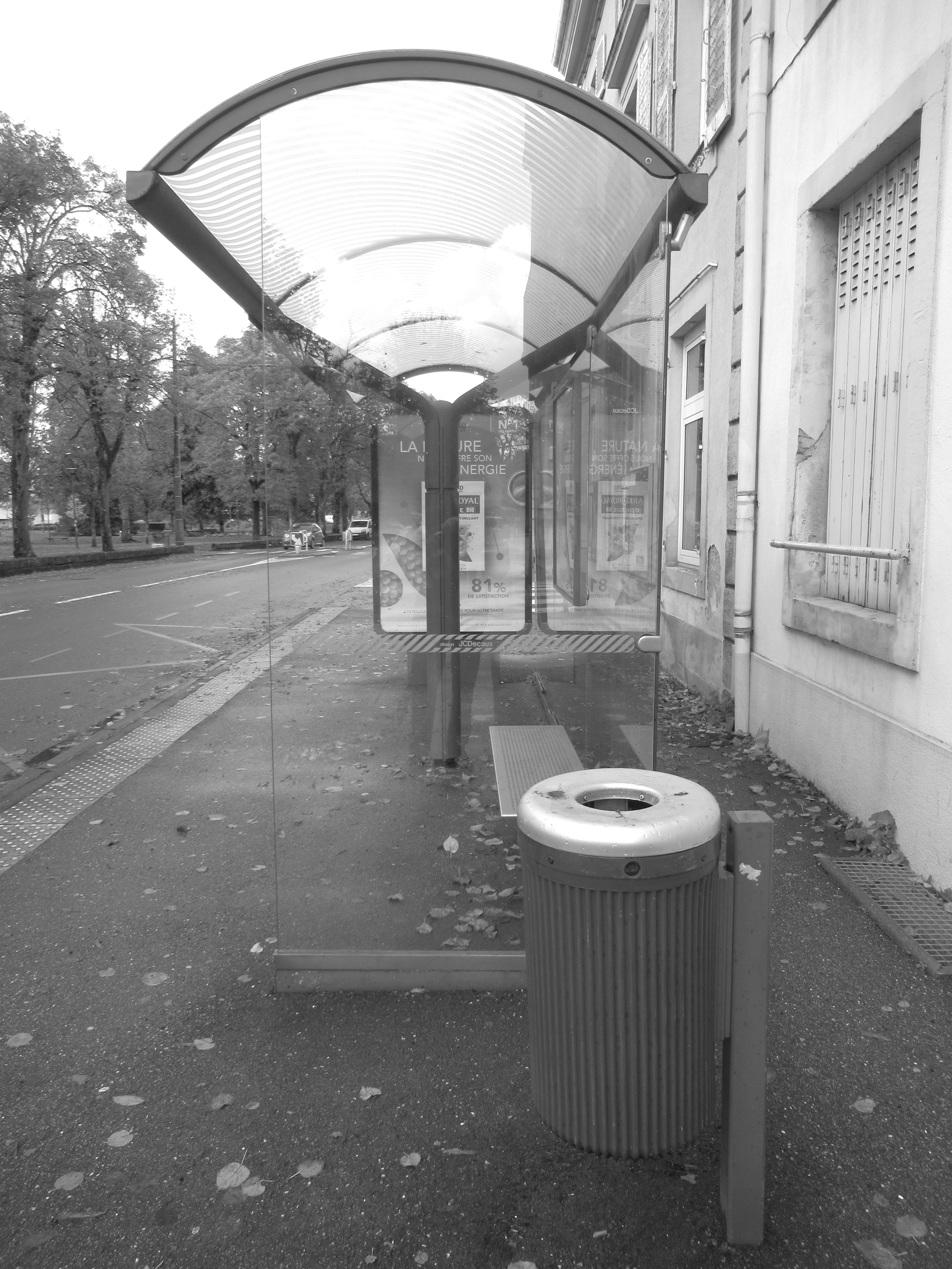 Poubelle publique près d'un abribus en verre