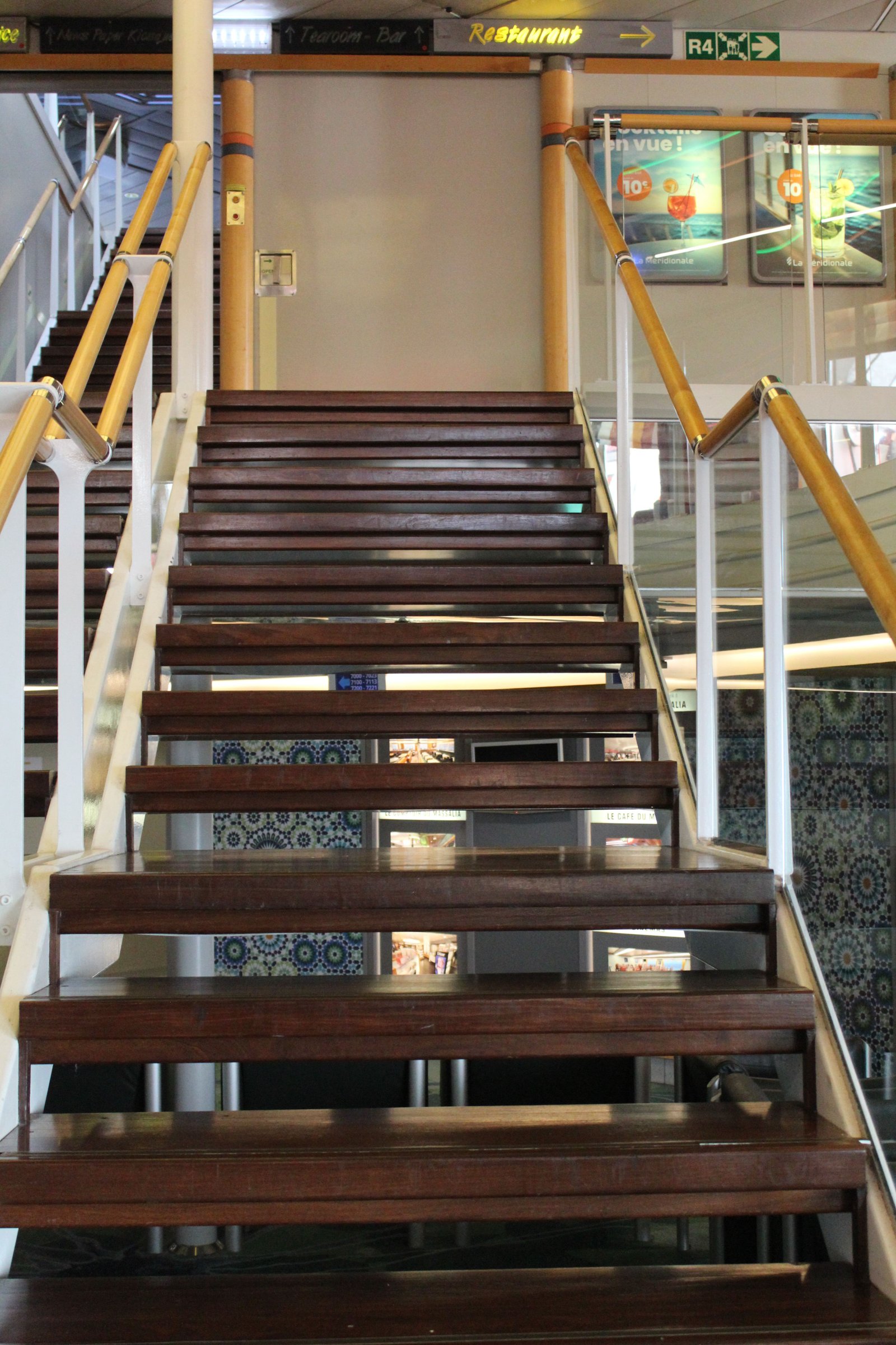 Un escalier intérieur, à bord d'un navire, avec des marches en bois et des rampes en bois et métal, photo gratuite
