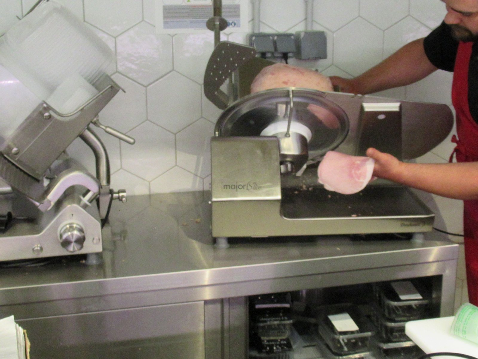 Homme découpant du jambon avec une trancheuse à jambon