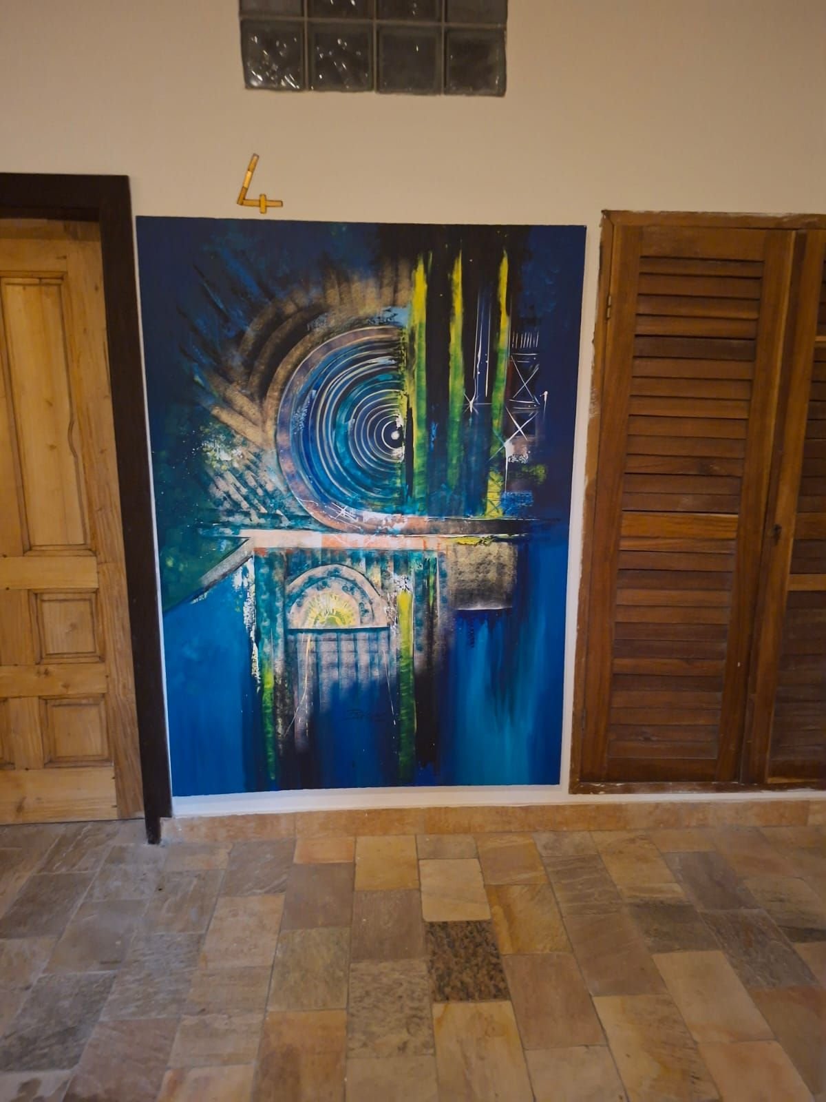Peinture acrylique abstraite accrochée sur un mur entre une porte en bois, photo gratuite