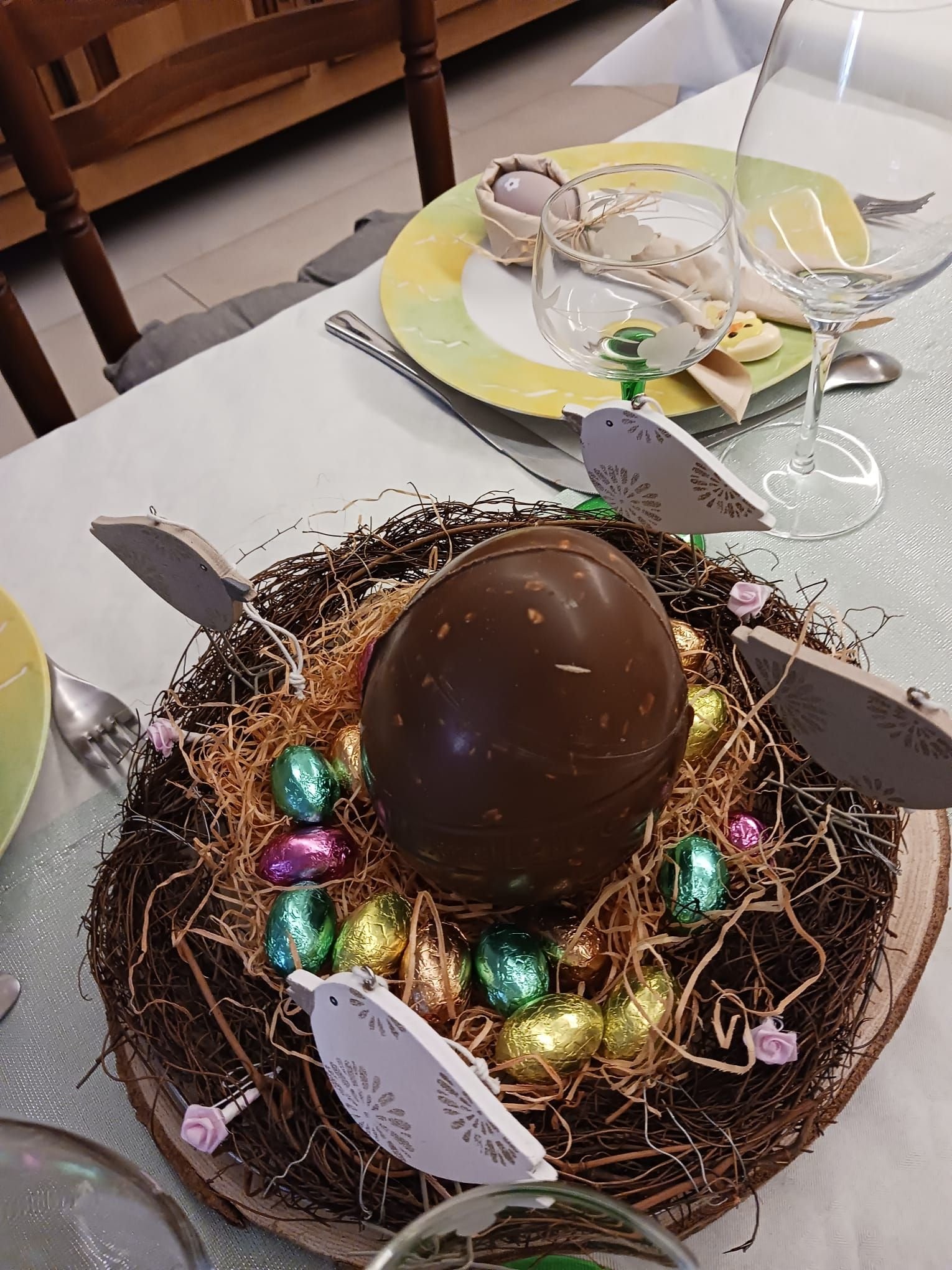 Une décoration de table festive centrée sur Pâques, avec un grand œuf en chocolat et de petits œufs colorés présentés dans un nid décoratif, photo gratuite