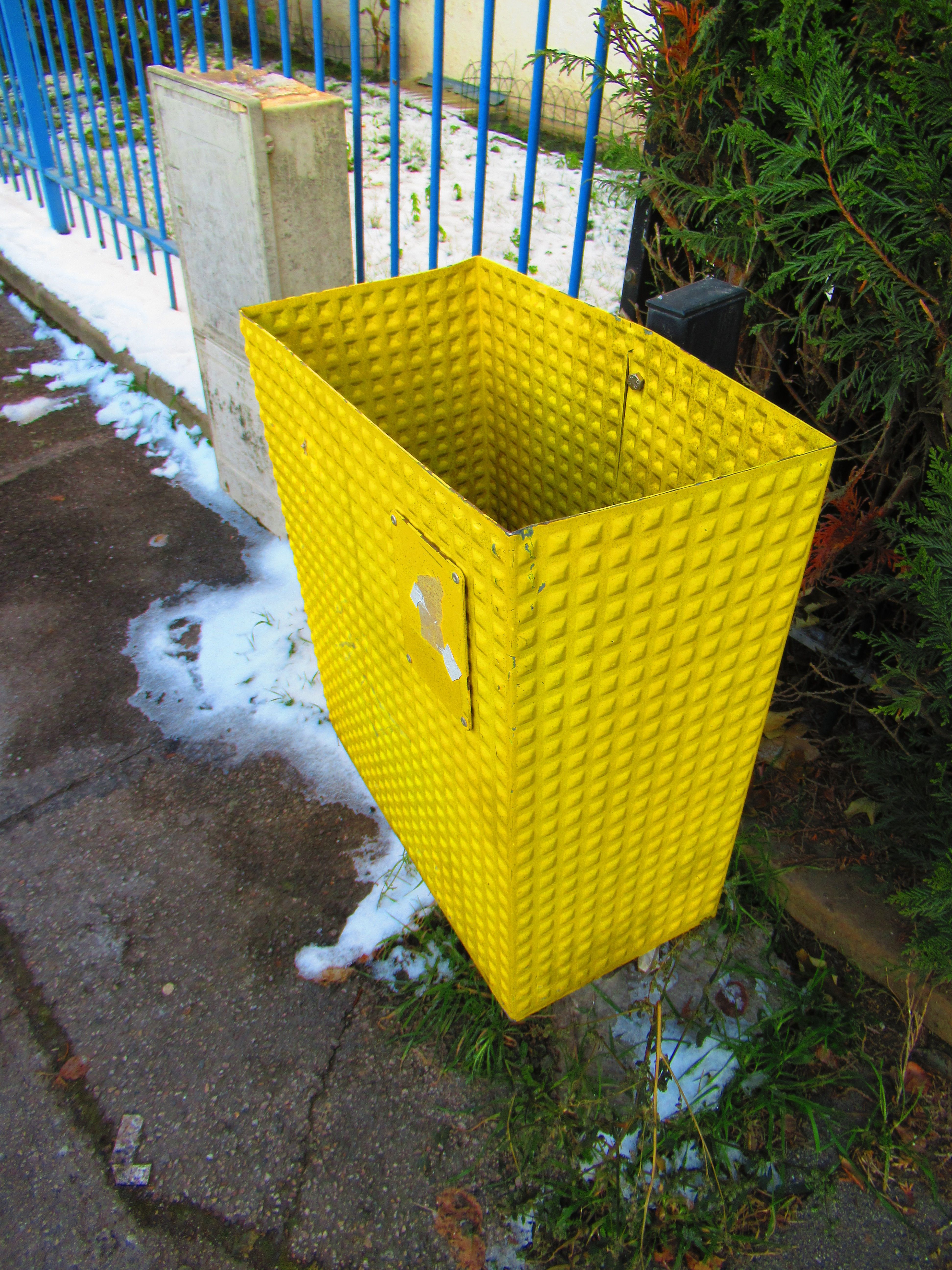 Poubelle de rue jaune sur trottoir