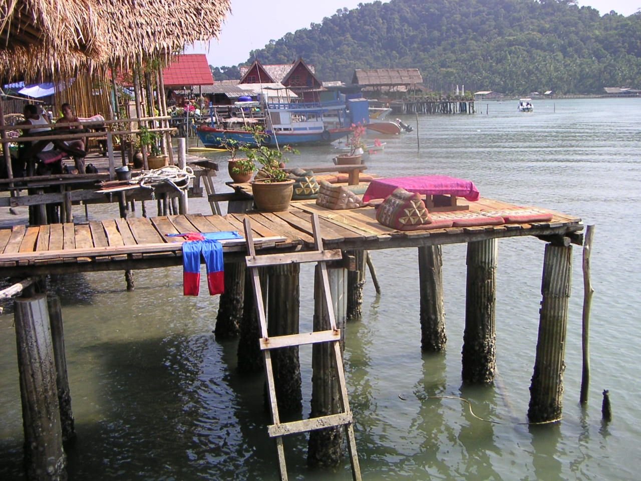 Une terrasse en bois avec des coussins et une échelle menant à l'eau, une construction sur pilotis au-dessus de l'eau, photo gratuite