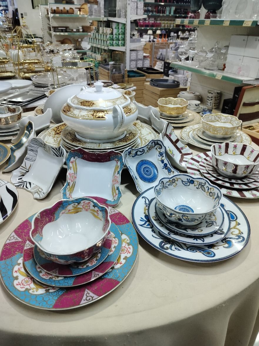 Des assiettes, des bols et une théière, exposés sur une table dans un rayon de magasin, photo gratuite