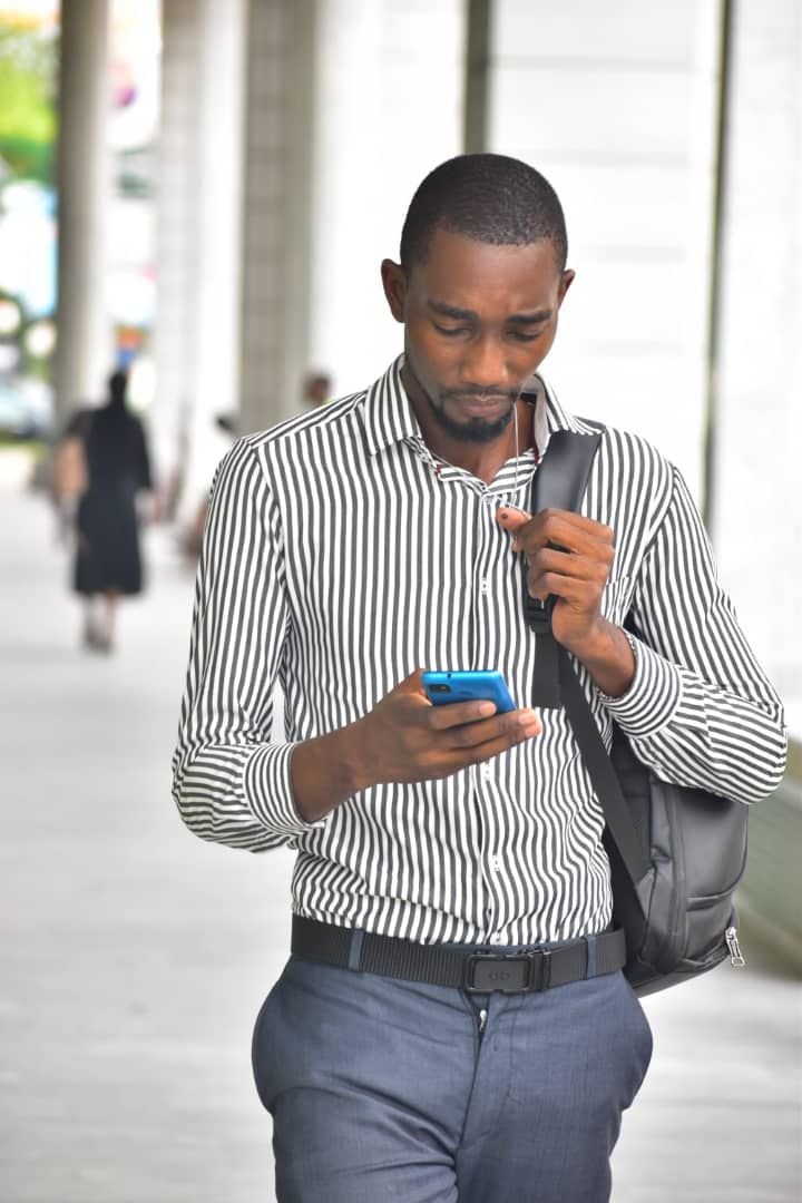 Un homme en pleine marche, absorbé par son téléphone photo gratuite