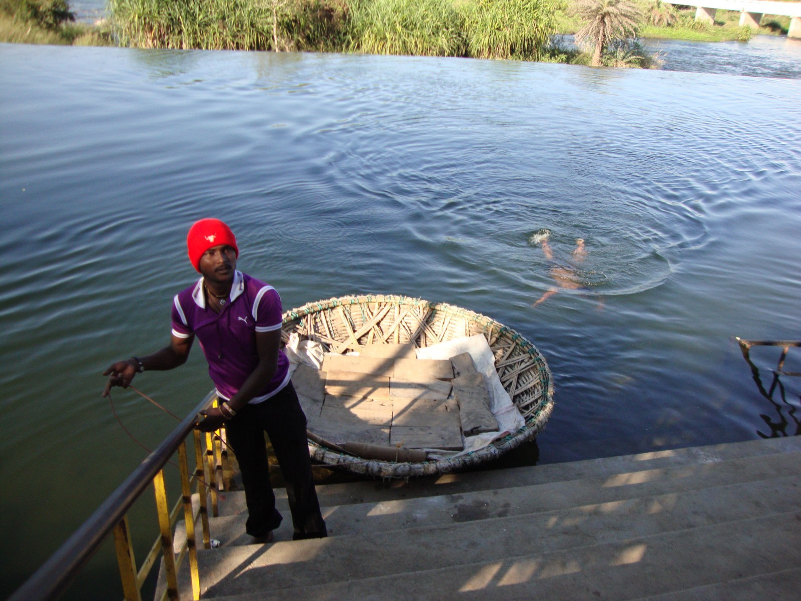 Une personne au bord de l'eau, une petite embarcation ronde et légère, traditionnellement utilisée pour la pêche ou le transport sur les rivières en Inde, photo gratuite