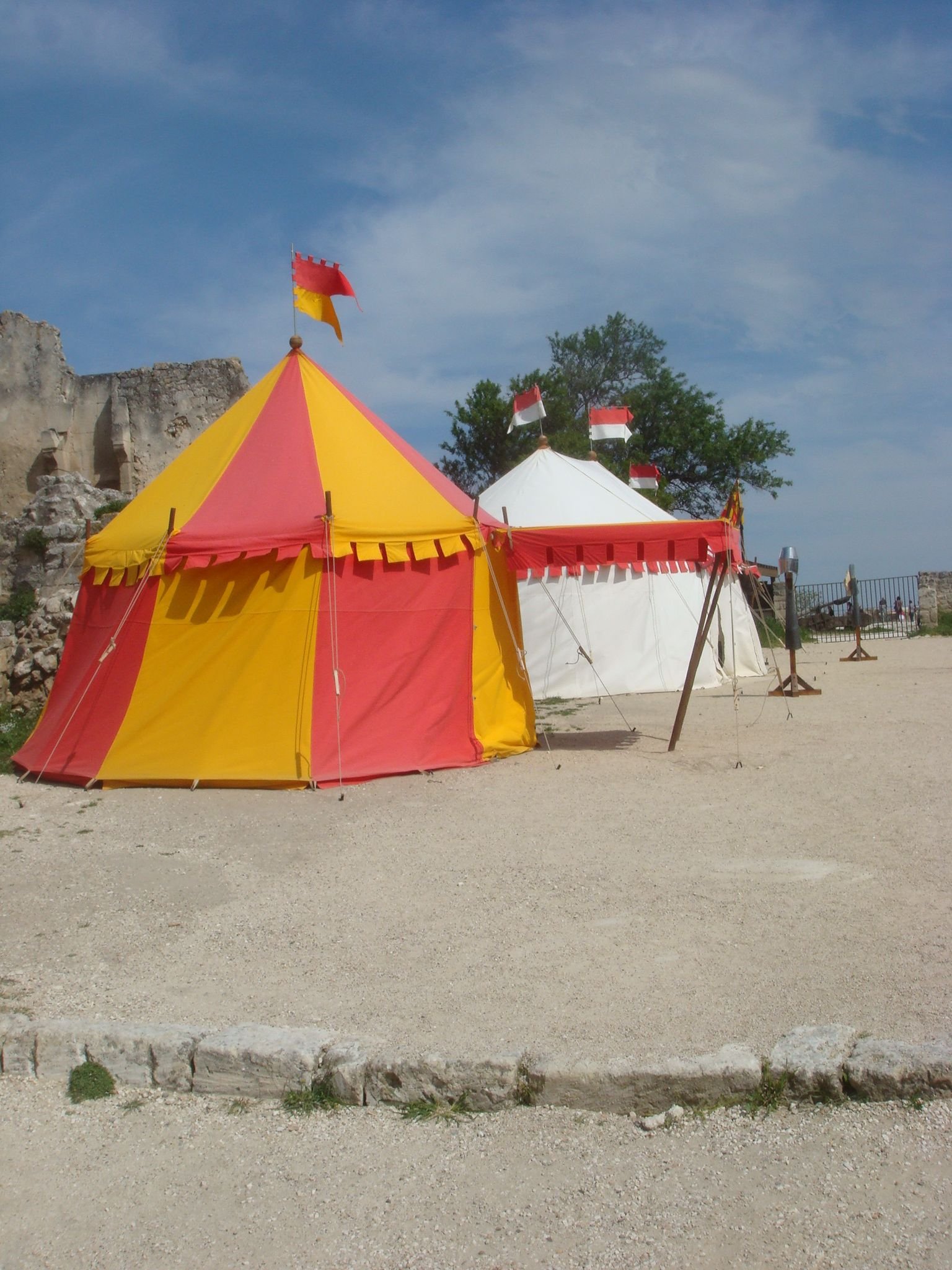 Deux tentes situées sur une surface en terre battue, avec un mur de pierre en ruine en arrière-plan photo gratuite - Zwei Zelte auf einer unbefestigten Fläche, mit einer zerstörten Steinmauer im Hintergrund, kostenloses Foto