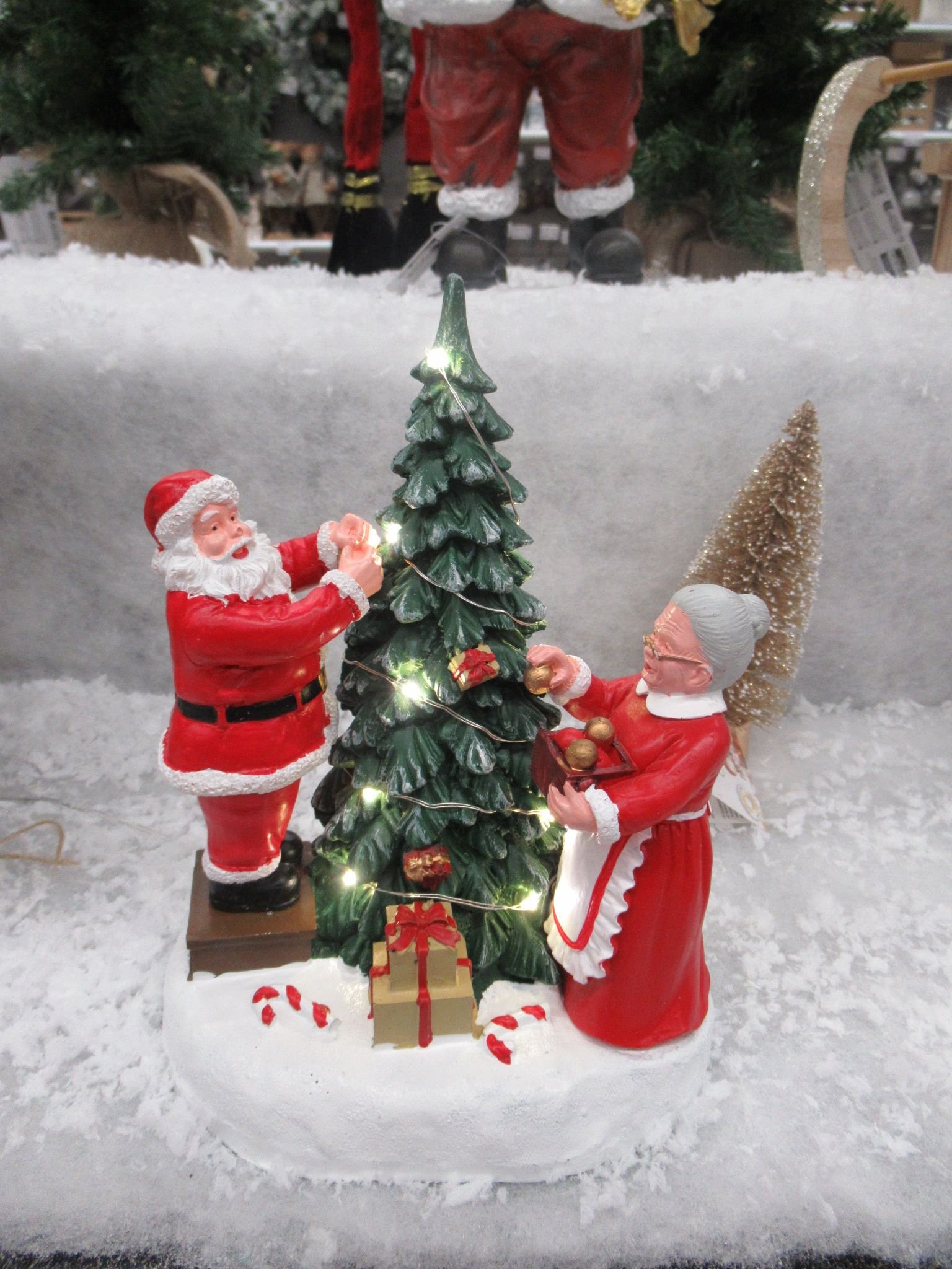 Une figurine représente le Père Noël et la Mère Noël décorant un sapin de Noël illuminé, photo gratuite