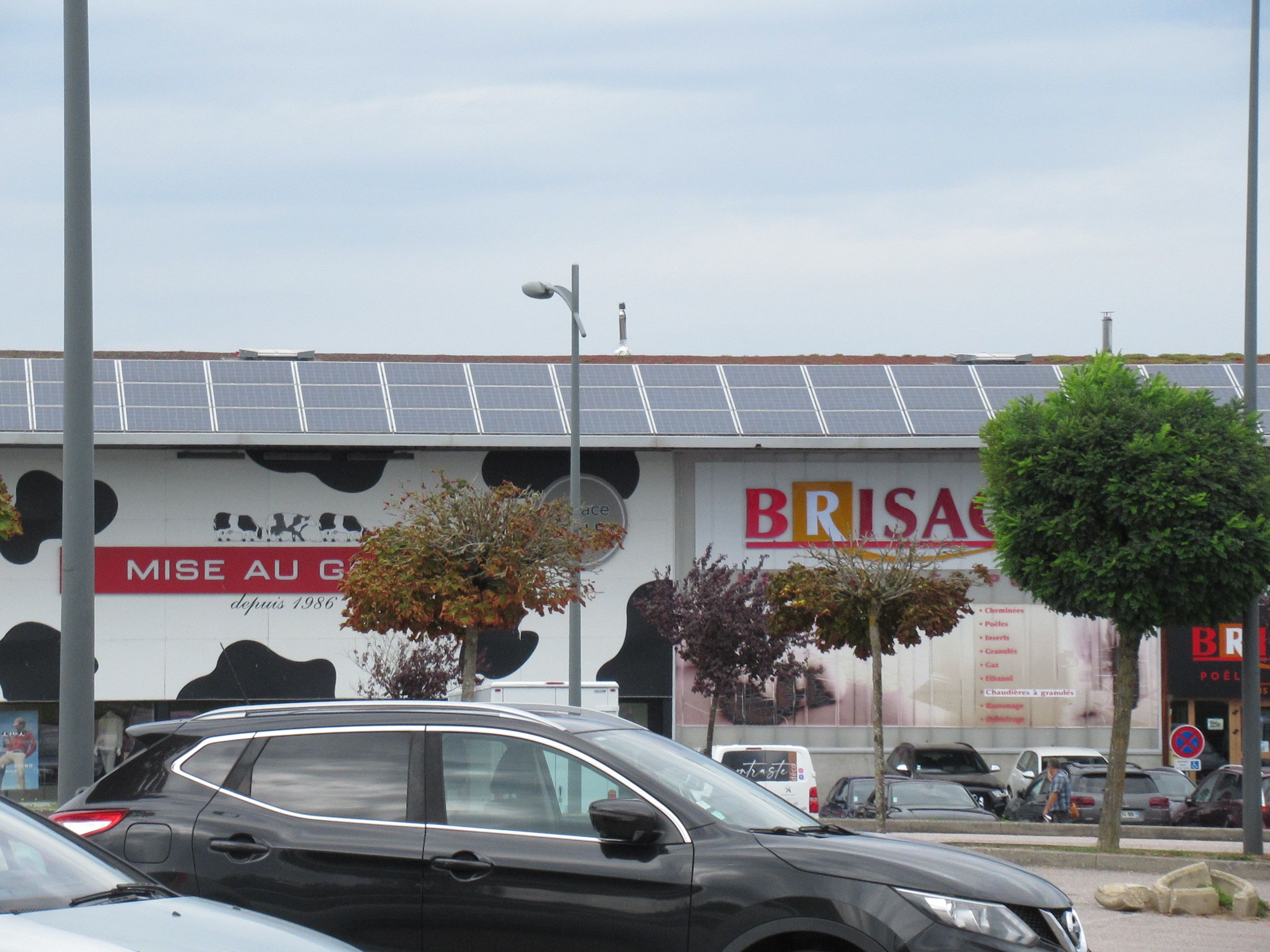 magasins MISE AU GREEN et BRISACH depuis un parking auto panneaux solaires