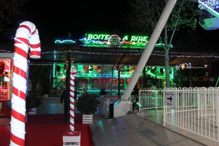 Une attraction de fête foraine nommée "Boîte à Rire", illuminée par des lumières vertes et colorées photo gratuite