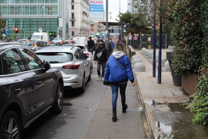 Personnes se baladant sur le trottoir, des voitures stoppées par un feu rouge, dans la ville de Milan Lombardie Italie photo gratuite