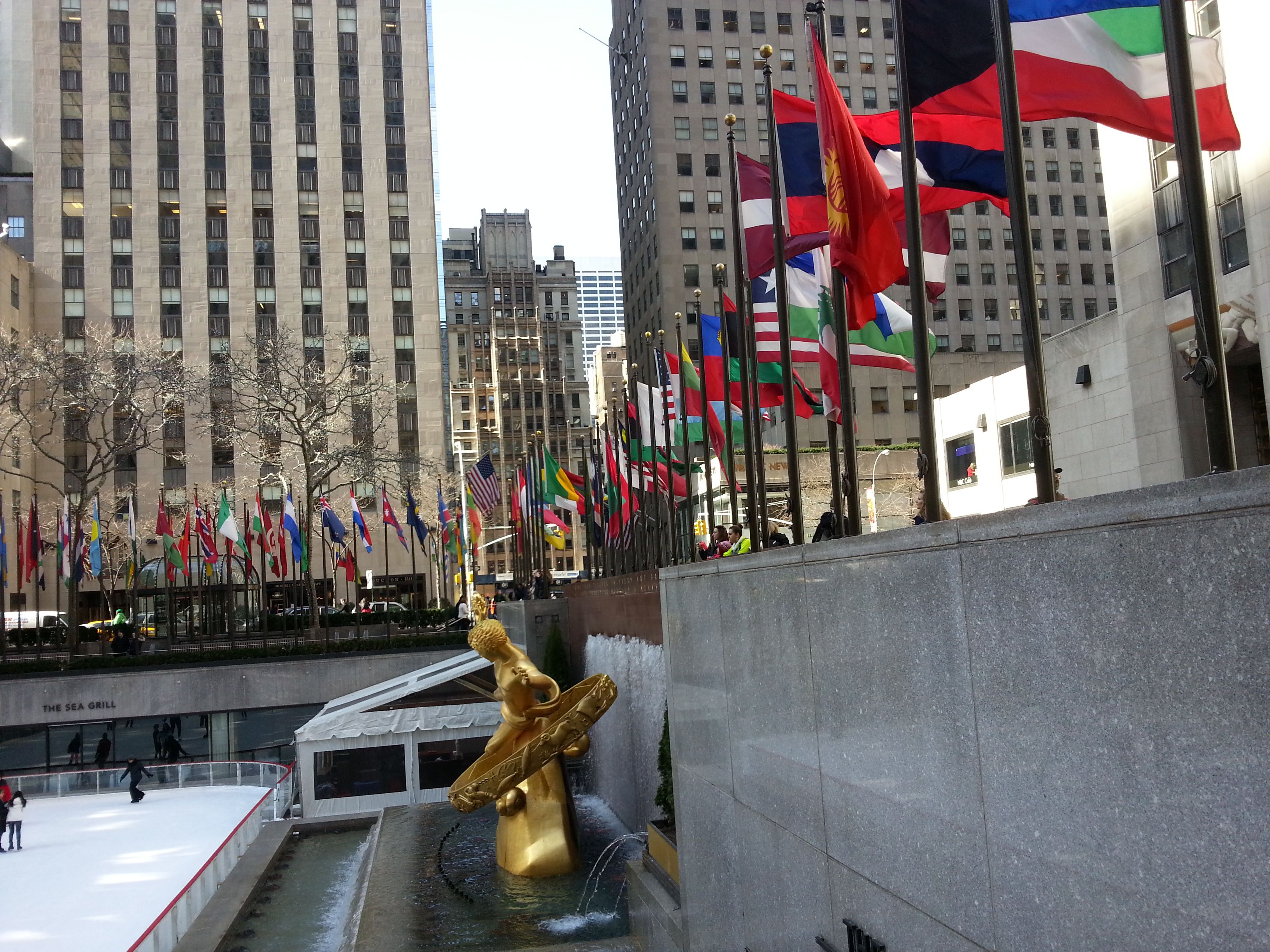 La statue d'or à la fontaine du Rockefeller Center, mémorial du 11 septembre, building, drapeaux des différents pays à New-York, Etats-Unis, photo gratuite