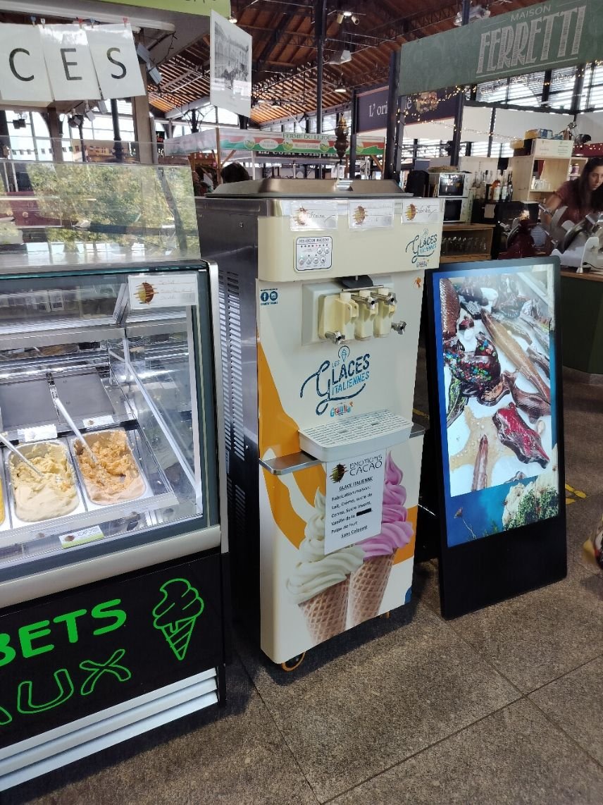 Une machine à glaces et une vitrine réfrigérée présentant différentes saveurs de glaces et de sorbets, photo gratuite