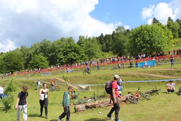 Une course de VTT dans un cadre rural, des spectateurs regardent les cyclistes sur une piste de terre, photo gratuite