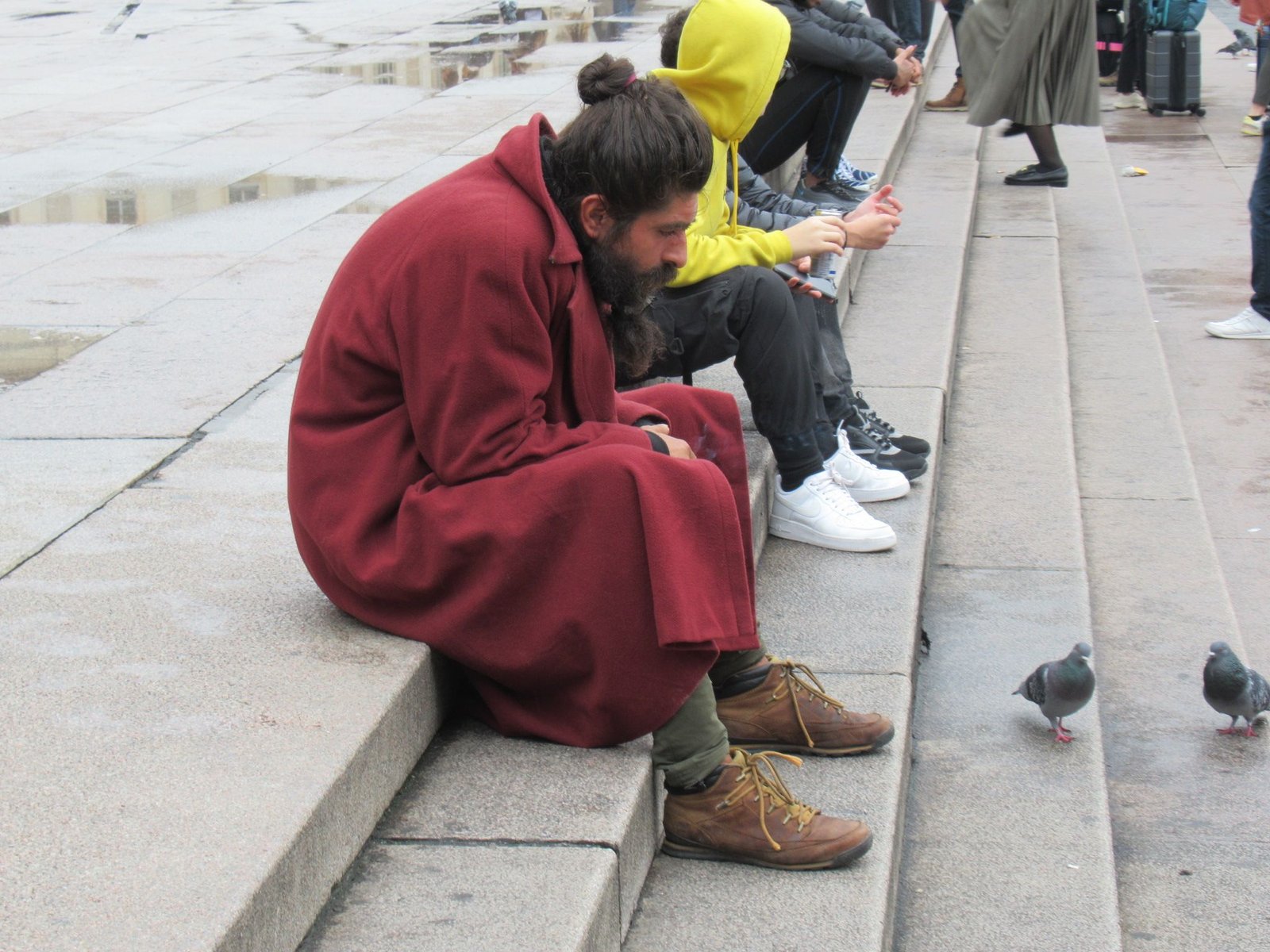 Homme en manteau rouge assis sur des marches photo gratuite
