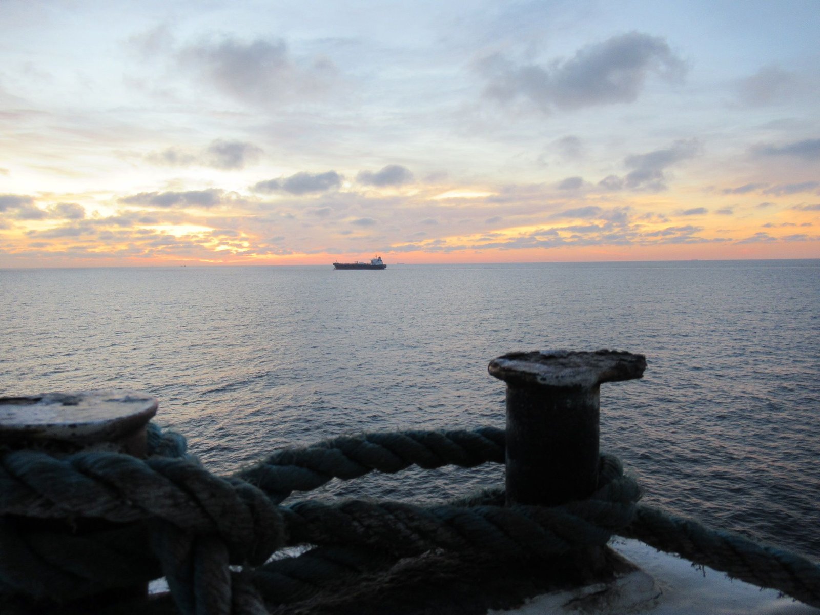 Corde épaisse est enroulée sur un bollard dans le port, bateau à l'horizon photo gratuite