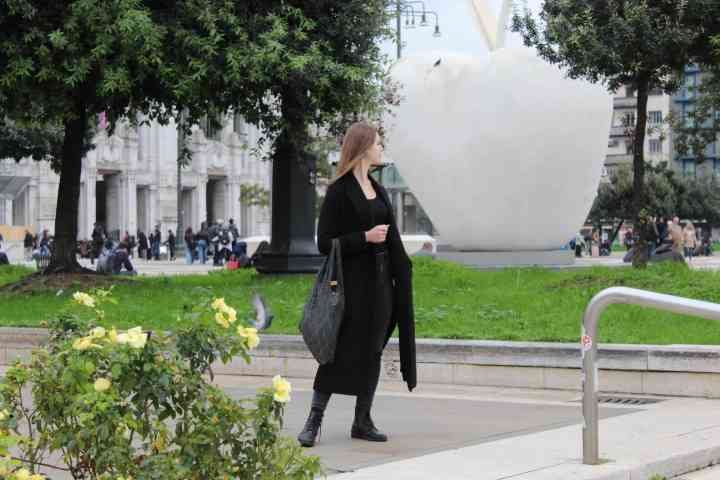 Femme habillée en noir, sac au bras, debout sur un espace public dans la ville de Milan Lombardie en Italie photo gratuite