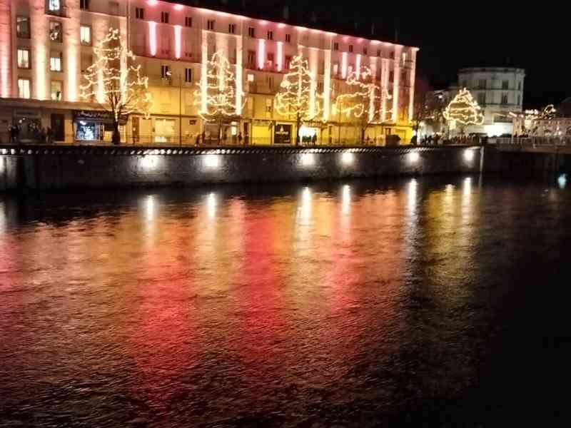 Bâtiment le long d'un cours d'eau la nuit, décoré d'illuminations festives, photo gratuite