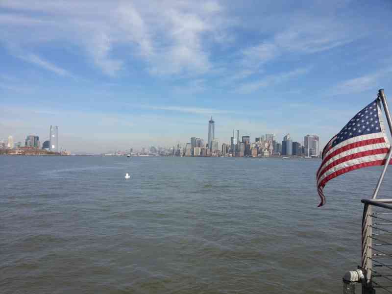 Drapeau américain accroché à un bateau sur le fleuve, vue de loin des immeubles de la ville de New-York, États-Unis, photo gratuite