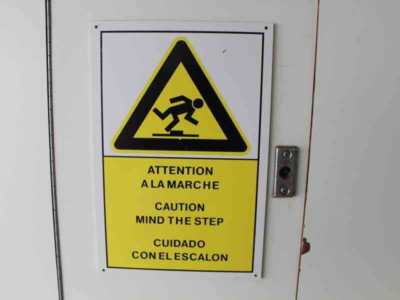 Un panneau d'avertissement de sécurité multilingue indiquant de faire attention à la marche, dans un bateau, photo gratuite