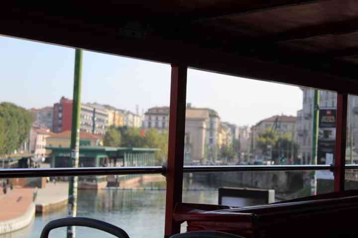 La vue depuis l'intérieur d'un véhicule, offrant une perspective sur une voie navigable bordée de bâtiments et d'une rue animée, photo gratuite