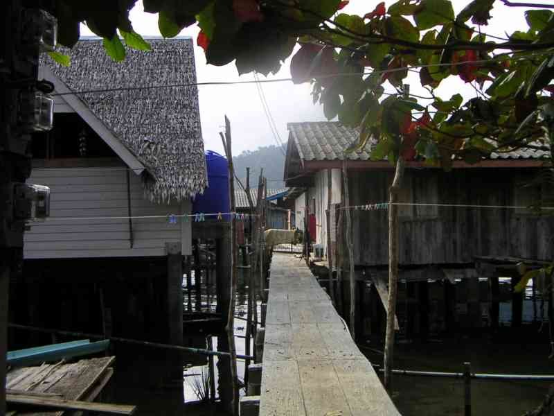 Un village de maisons sur pilotis, construit au-dessus de l'eau, avec une passerelle en bois reliant les habitations, photo gratuite