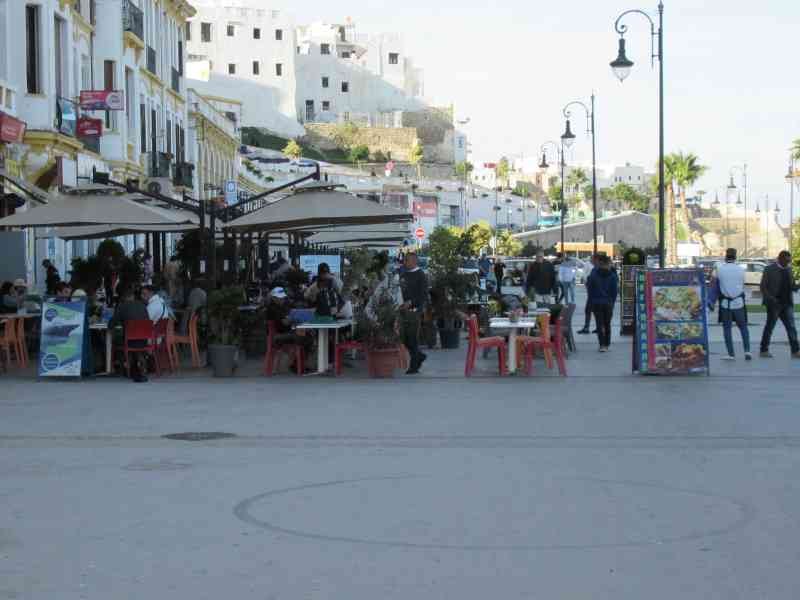 Personnes assises dans un restaurant de rue devant l'immeuble Renschhausen à Tanger au Maroc