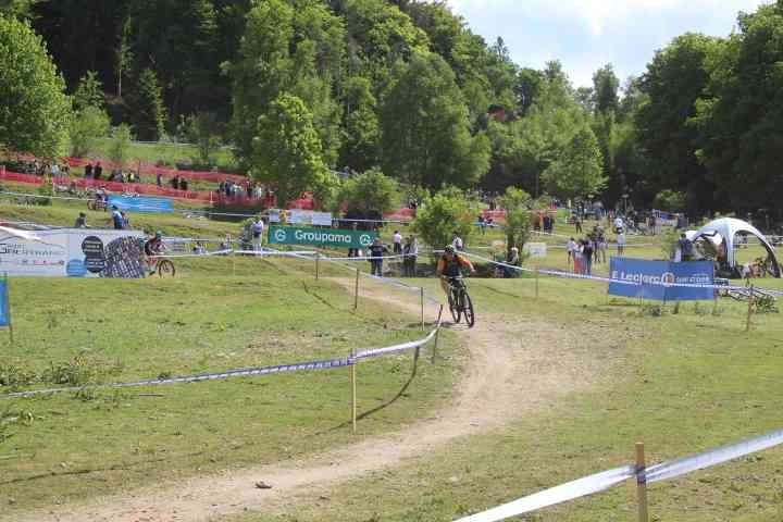 Course de VTT, le cycliste suit un parcours balisé par des rubans, avec des spectateurs observant depuis les collines environnantes photo gratuite