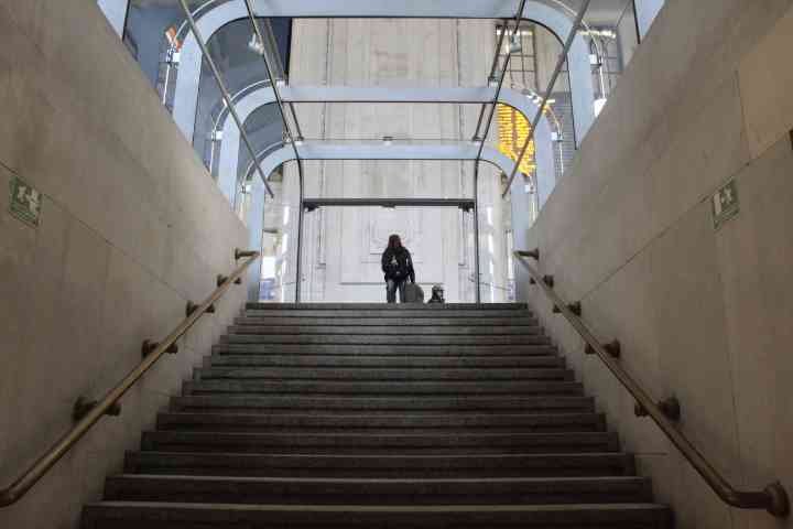 Une personne avec une valise à la main s'apprête à descendre les escaliers en béton, à l'intérieur d'un bâtiment dans la ville de Milan Lombardi en Italie photo gratuite