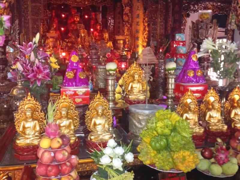 Autel décoré avec des statues de Bouddha dorées et des offrandes traditionnelles, Vietnam, photo gratuite